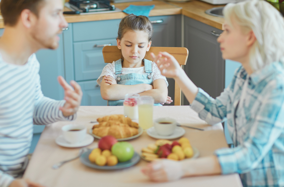 Trauma Nutrition Blog featured image A school-aged girl looks frustrated while her parents argue at the kitchen table