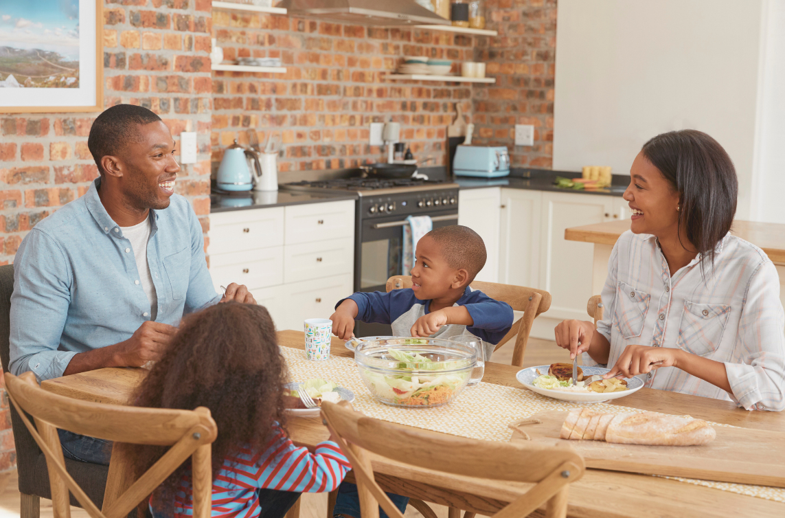 family meal plan blog featured image A black mother and father are enjoying a meal in their kitchen with their young son and daughter.