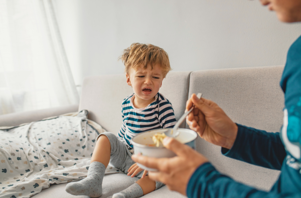 a toddler cries looking at a bowl of food a caregiver is offering him
