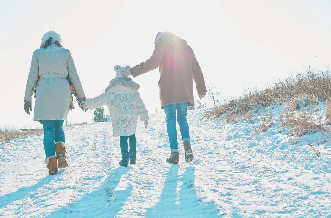 vitamin D blog post featured image back shot of a mother, daughter, and father walking in the snow on a sunny winter day