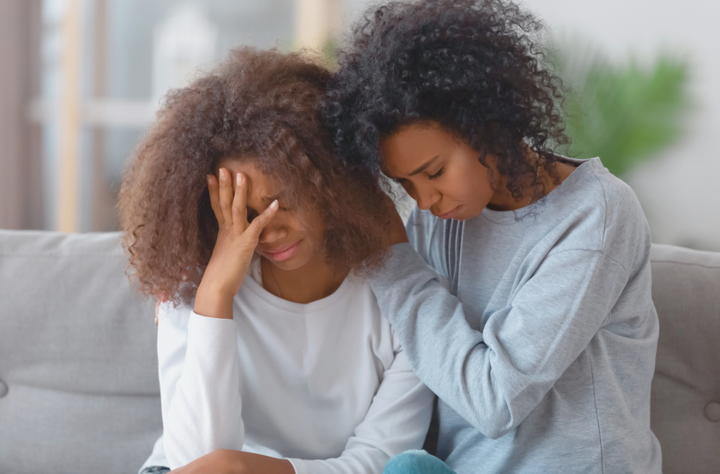 daughter with head in hands looking disappointed while mom rests her head on hers looking supportive
