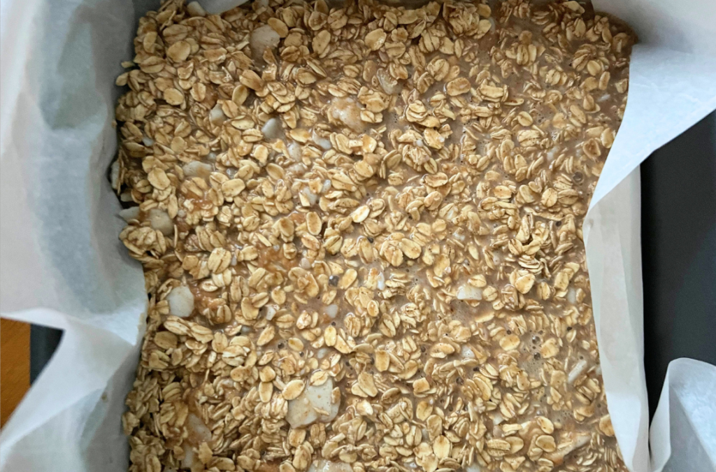 oatmeal bake batter poured in a square baking dish lined with parchment paper