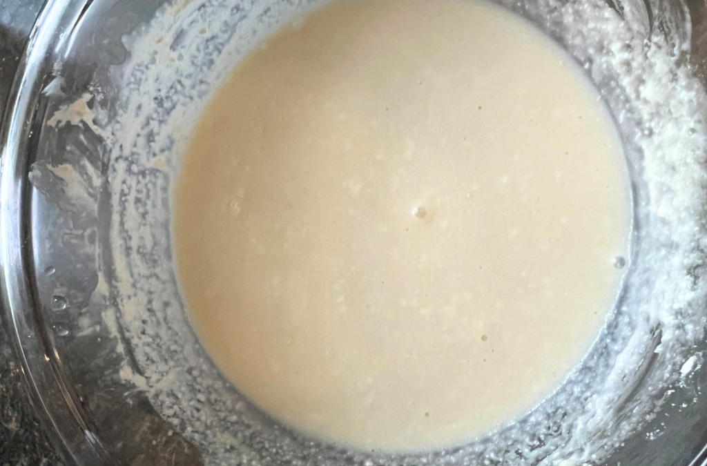 cream cheese icing mixed in a clear glass bowl